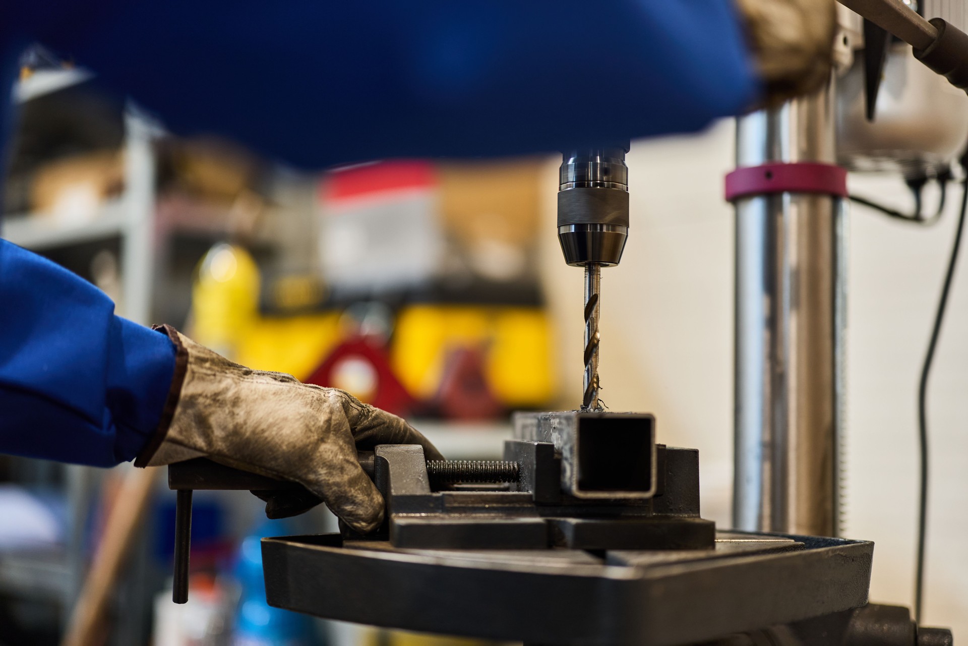 Industrial Workshop Drill Press and Worker Handling Metal Component